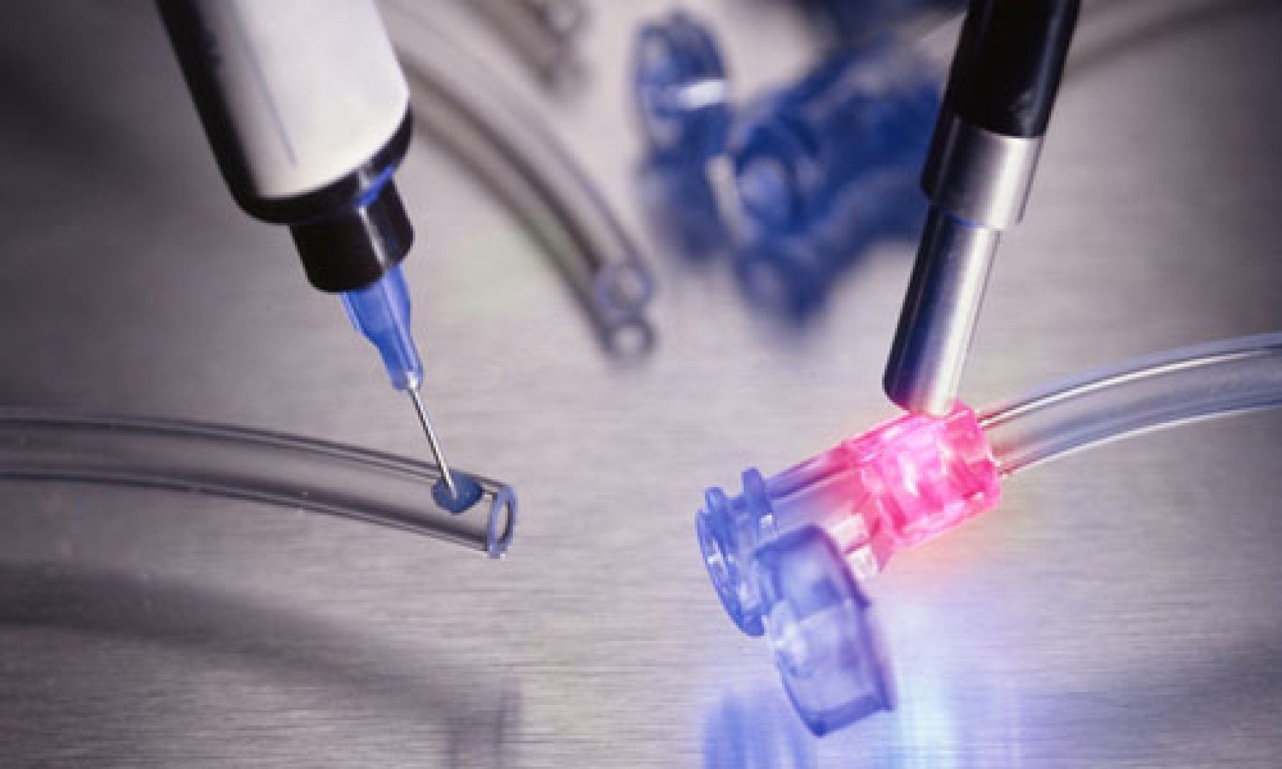 A Dymax adhesive with See-Cure and Ultra-Red fluorescing is dispensed onto a tube set and then cured with a spot curing light guide.